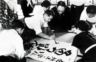 Ikeda encouraginf Soka Gakkai members with the calligraphy--Courageous Struggle