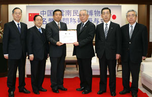 El director Xie (3º desde la izquierda) coloca en manos del presidente de la Asociación de Conciertos Min-On (3º desde la derecha) el certificado honorífico destinado a Daisaku Ikeda