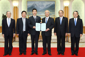 El presidente de la Universidad de Hebei (tercero desde la izquierda) deposita en las manos del presidente de la Universidad Soka un documento honorífico para Daisaku Ikeda