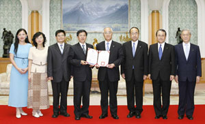 Tang Yen-Po (cuarto desde la izquierda), presidente del Instituto Tecnológico Chungyu, coloca el diploma del profesorado honorario destinado a Daisaku Ikeda en manos de Hideo Yamamoto, presidente de la Universidad Soka (cuarto desde la derecha)